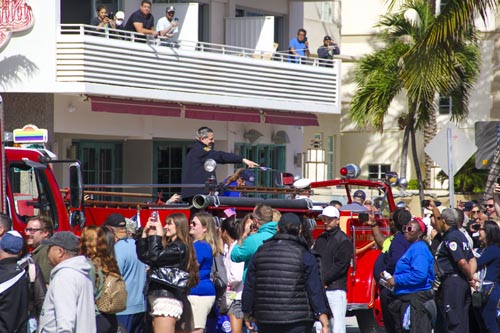 Mayor Meiner on top of Miami Beach fire truck pointing into crowd