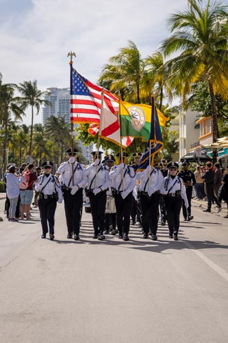people marching holding USA, Florida and Miami Beach flags