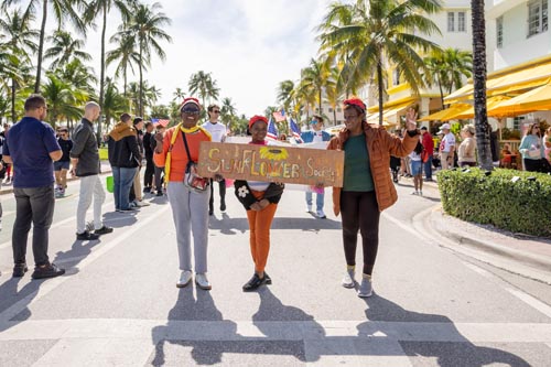 people walking while holding "Sunflower Society" sign