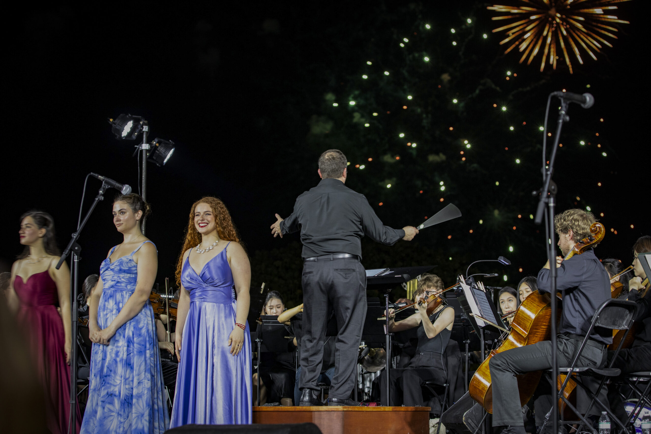 on stage performance with orchestra, conductor and singers. A firework is in the sky.