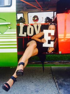 woman posing in a car holding the letters spelling out "love"