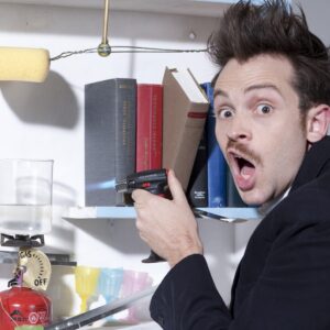 man photographed holding books in his hand that are on a shelf