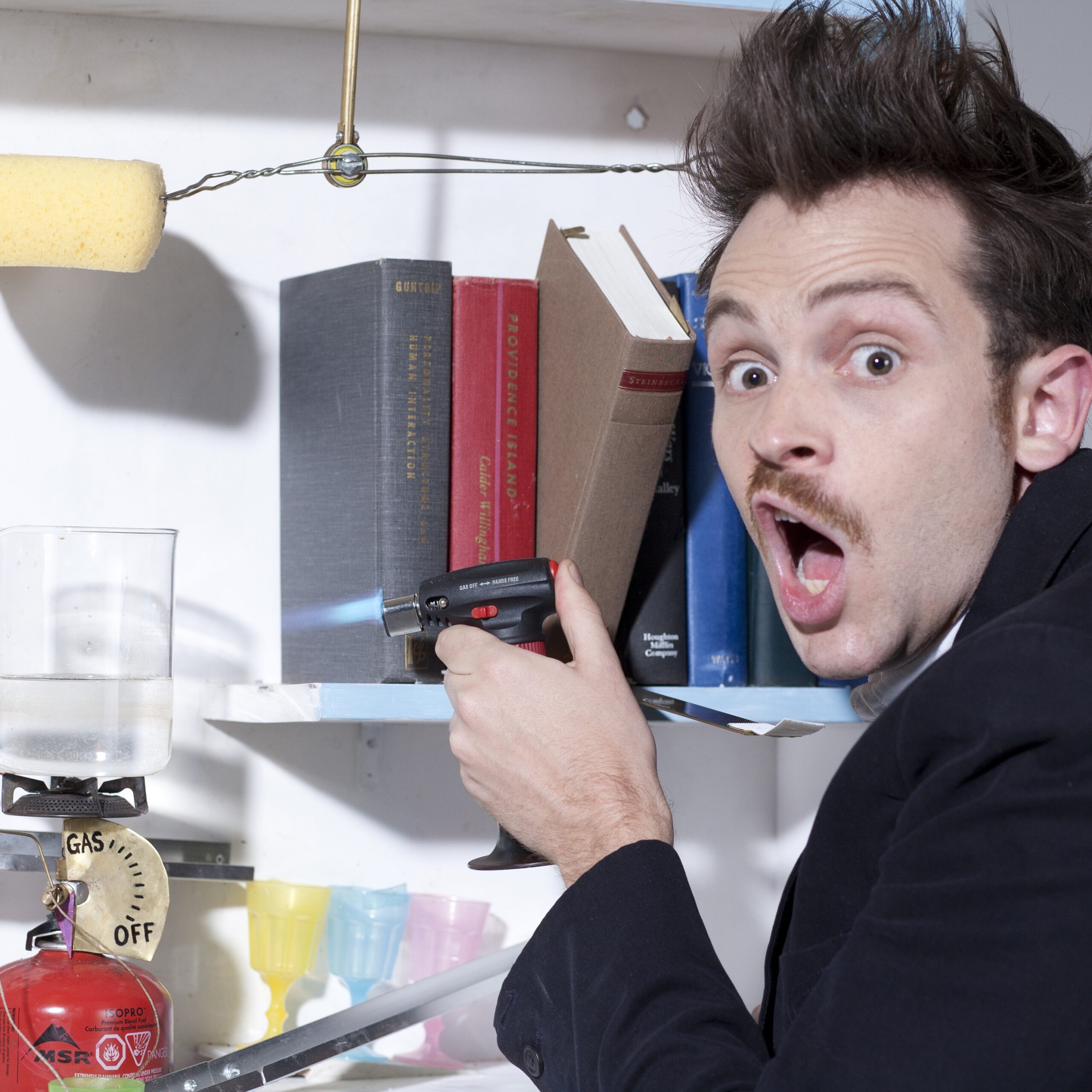 man photographed holding books in his hand that are on a shelf