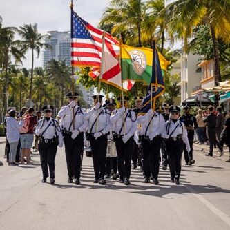 people marching holding USA, Florida and Miami Beach flags